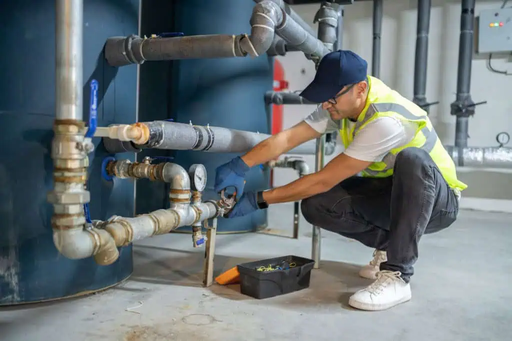 Technician Repairing Heating System Pipes In The Boiler Room Technician Repairing Heating System Pipes In The Boiler Room